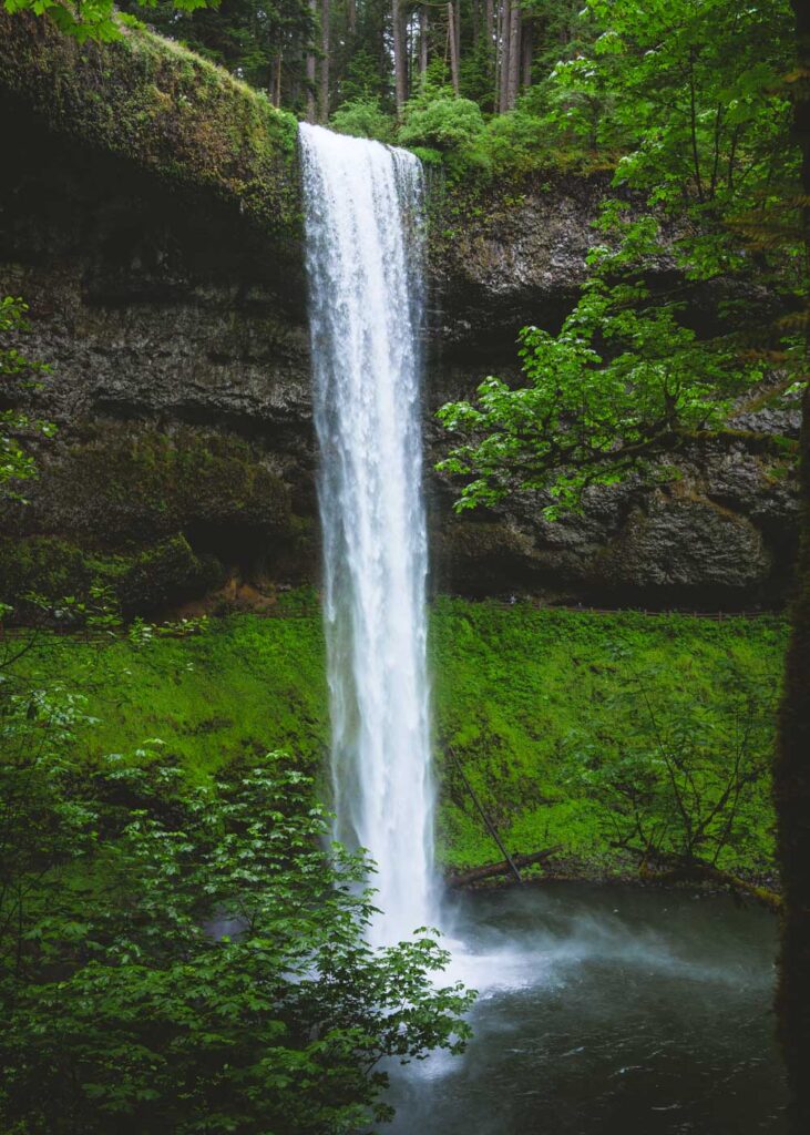 Tall waterfall at Trail of 10 Falls with greenery on the surrounding rocks.