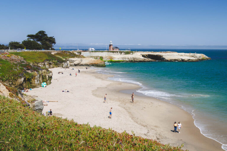 Lighthouse Beach scene in Santa Cruz with sunbathers and azure waters.