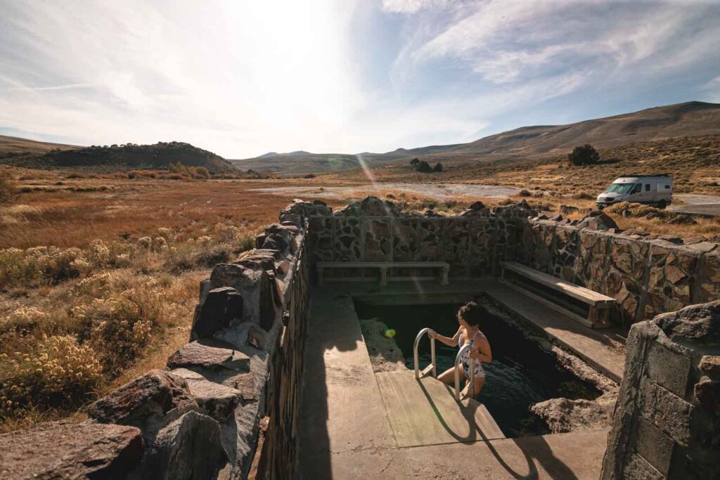 Nina getting out of the Hart Mountain Hot Spring with a desert setting in the back.