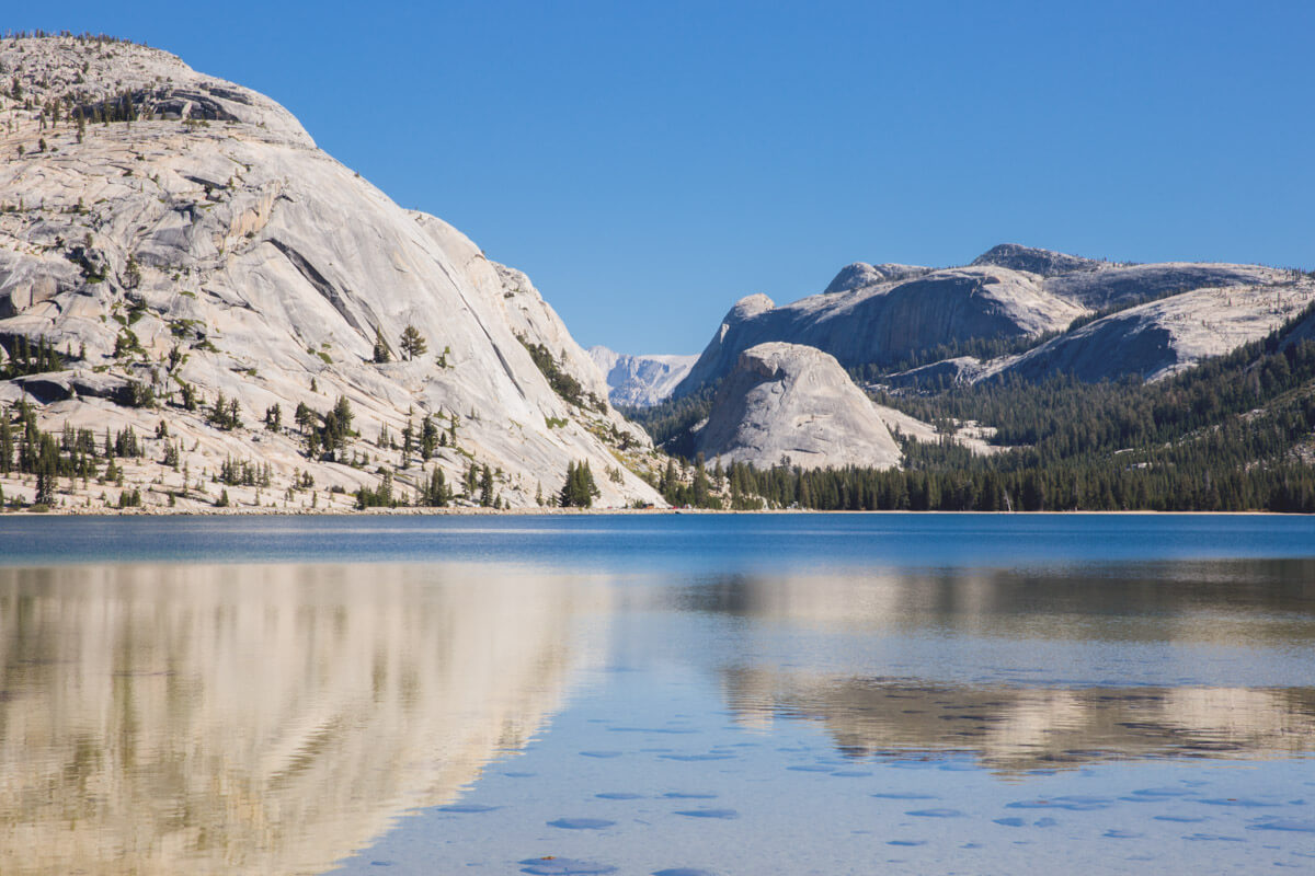 Mountains reflected in the still blue water of Tenaya Lake along Tioga Road in Yosemite National Park