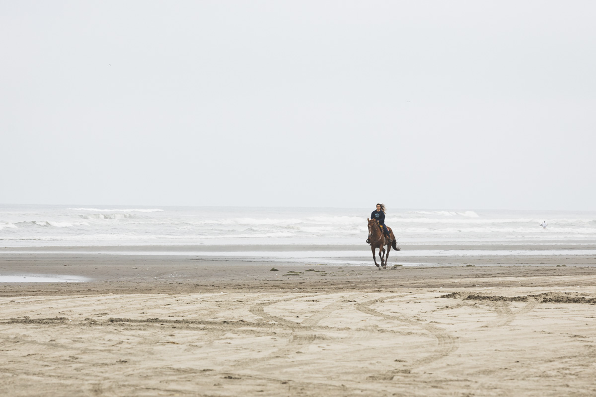 Woman riding a horse along the beach at Long Beach, Washington