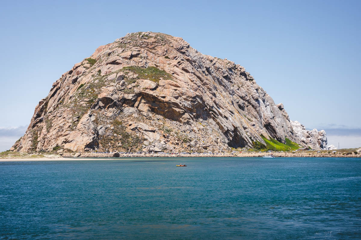 Kayakers paddling the protected estuary at Morro Bay State Park with Morro Rock in the background.