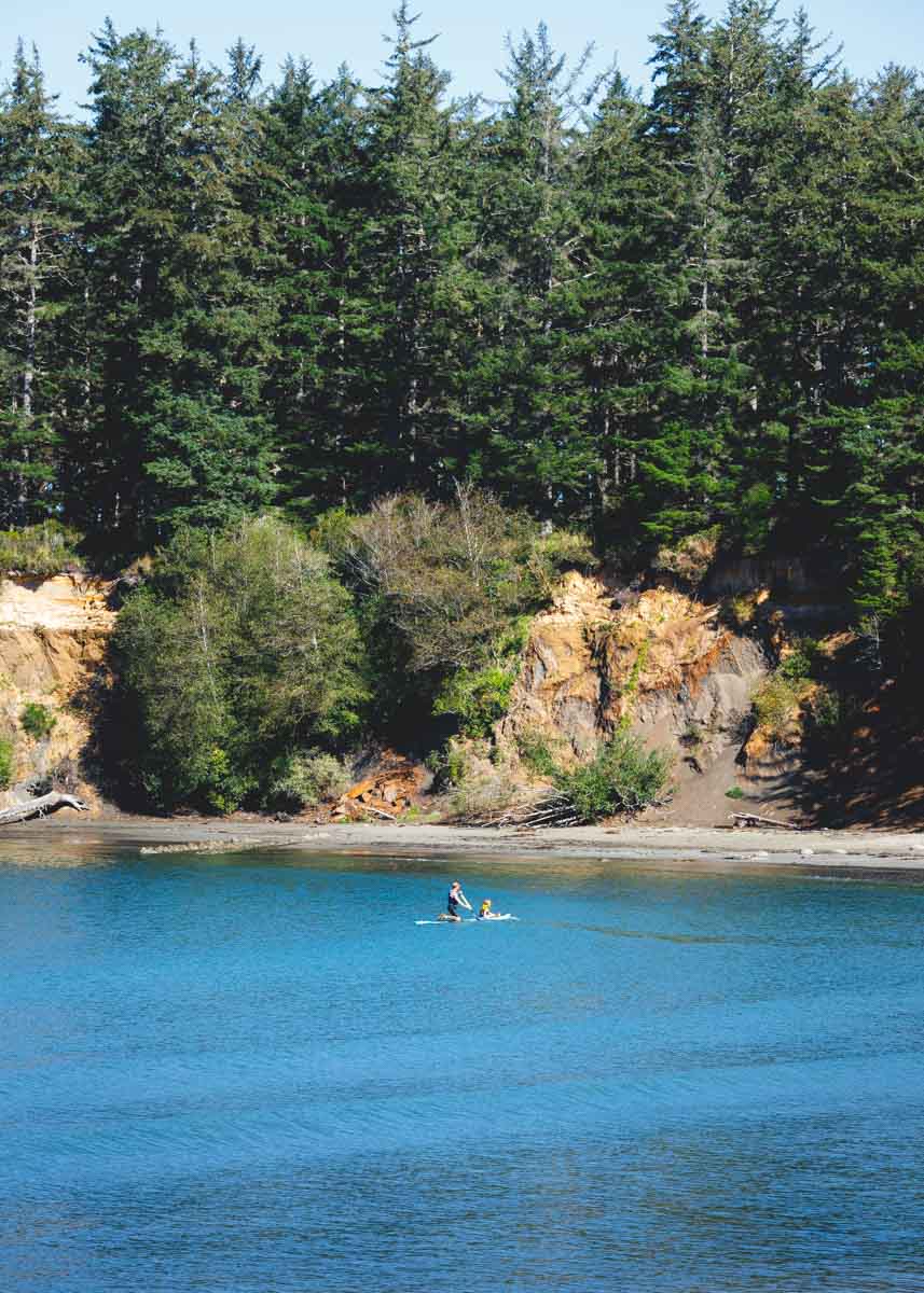A paddleboarder on the calm, protected water of Sunset Bay State Park on the Oregon coast.